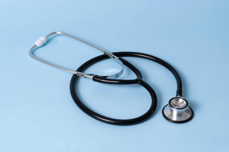 Estetoscópio preto e cinza sobre fundo azul claro, símbolo de profissionais de saúde e medicina.